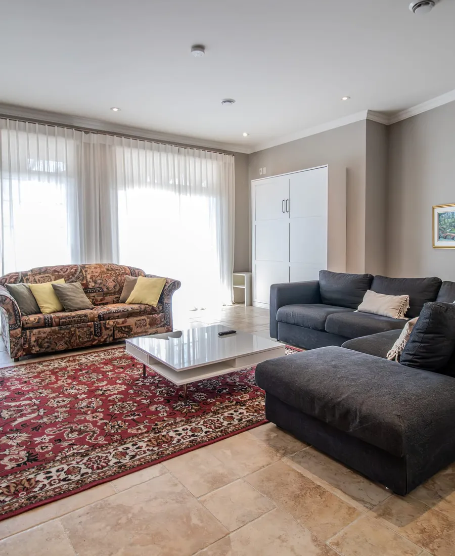 Salon avec canapé sombre et tapis fleuri